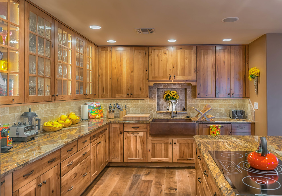 Open concept kitchen - large rustic u-shaped medium tone wood floor open concept kitchen idea in Phoenix with a farmhouse sink, shaker cabinets, medium tone wood cabinets, granite countertops, beige backsplash, stone tile backsplash, stainless steel appliances and an island