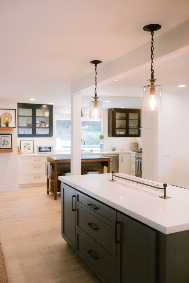 Rural kitchen in Los Angeles with white splashback, light hardwood flooring, an island, brown floors and white worktops.