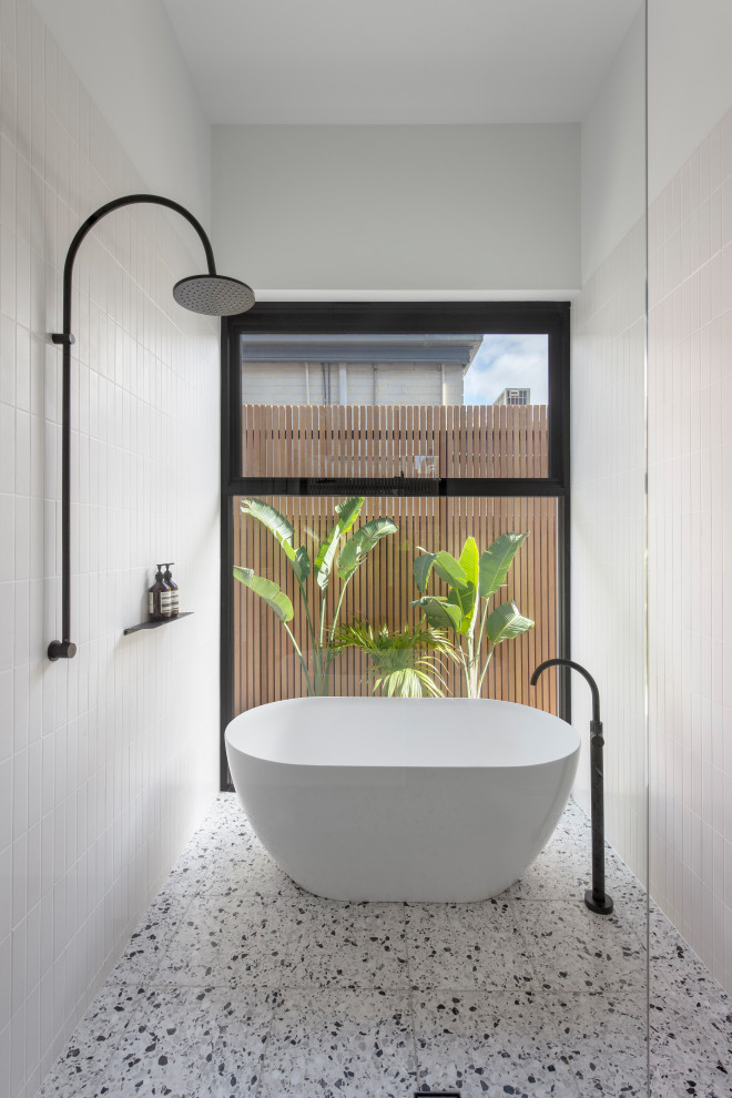 Design ideas for a mid-sized contemporary master bathroom in Adelaide with recessed-panel cabinets, white cabinets, a freestanding tub, an open shower, white tile, ceramic tile, white walls, terrazzo floors, solid surface benchtops, white floor, an open shower, white benchtops, an enclosed toilet, a single vanity, a floating vanity and wood walls.