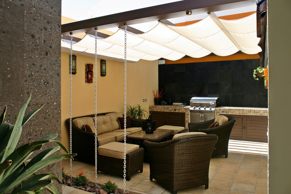 Photo of a small modern backyard patio in Other with an outdoor kitchen, an awning and tile.