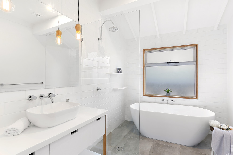 Transitional bathroom in Brisbane with flat-panel cabinets, white cabinets, a freestanding tub, white tile, white walls, a vessel sink and grey floor.