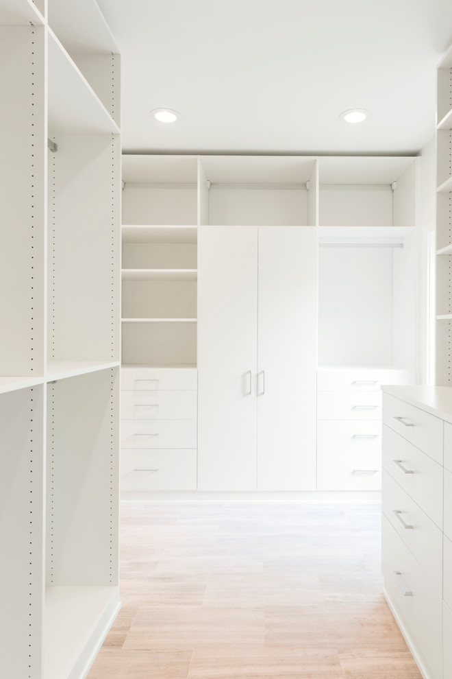 Large contemporary gender-neutral walk-in wardrobe in Dallas with limestone floors, beige floor, flat-panel cabinets and white cabinets.