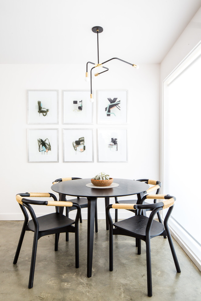 Photo of a scandinavian dining room in Los Angeles with white walls, concrete floors and grey floor.