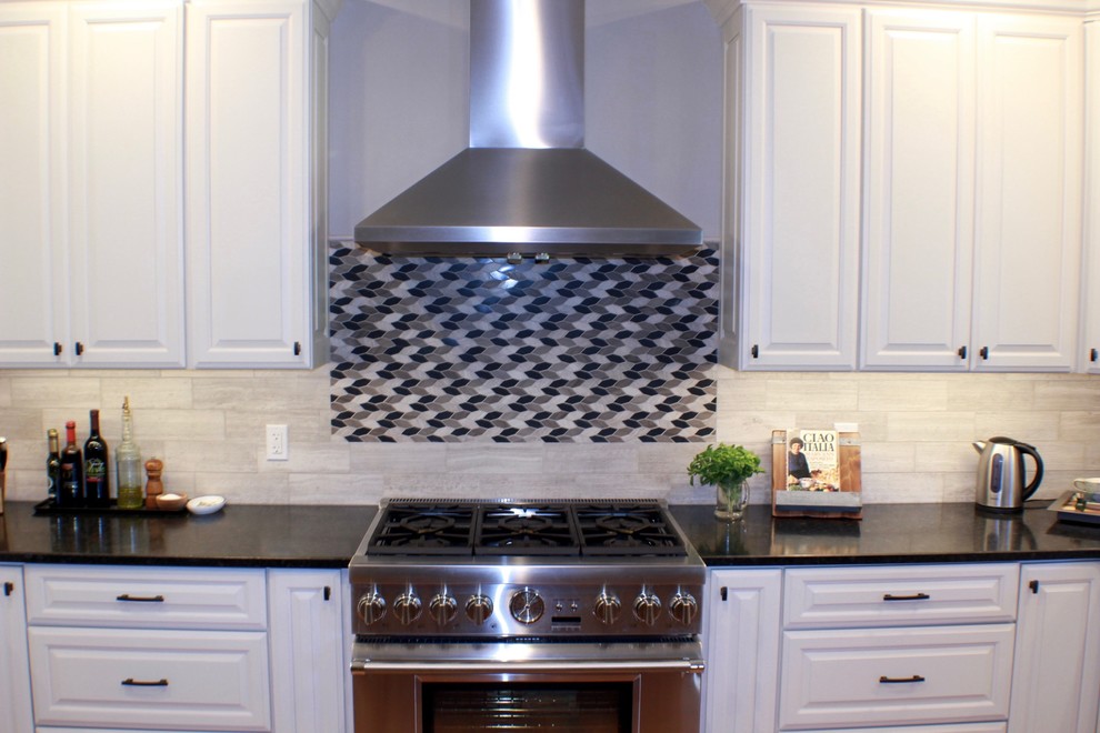 Eat-in kitchen - mid-sized transitional l-shaped medium tone wood floor and brown floor eat-in kitchen idea in Cincinnati with an undermount sink, raised-panel cabinets, white cabinets, granite countertops, gray backsplash, limestone backsplash, stainless steel appliances and an island