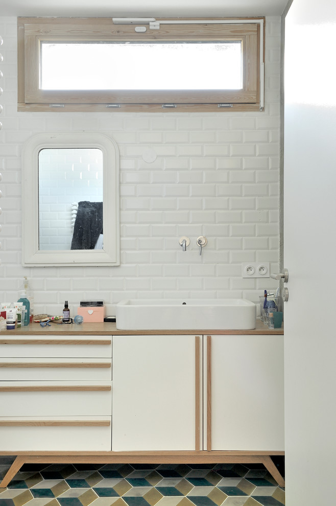 Photo of a mid-sized scandinavian master bathroom in Lyon with white cabinets, white walls, ceramic floors, a vessel sink, wood benchtops, white tile, subway tile and brown benchtops.