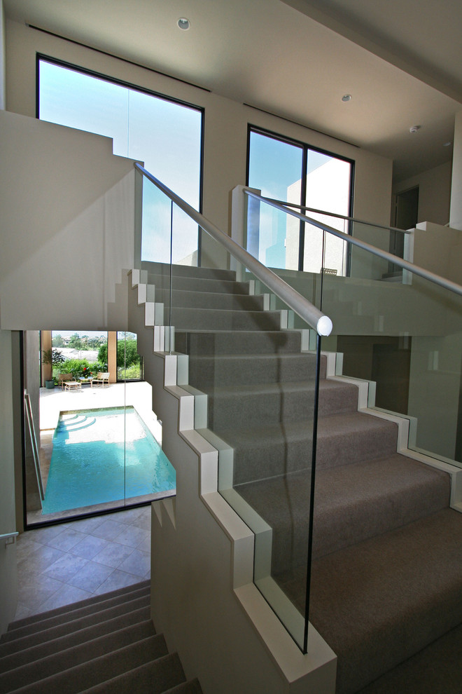 Photo of a contemporary carpeted staircase in San Diego with carpet risers.