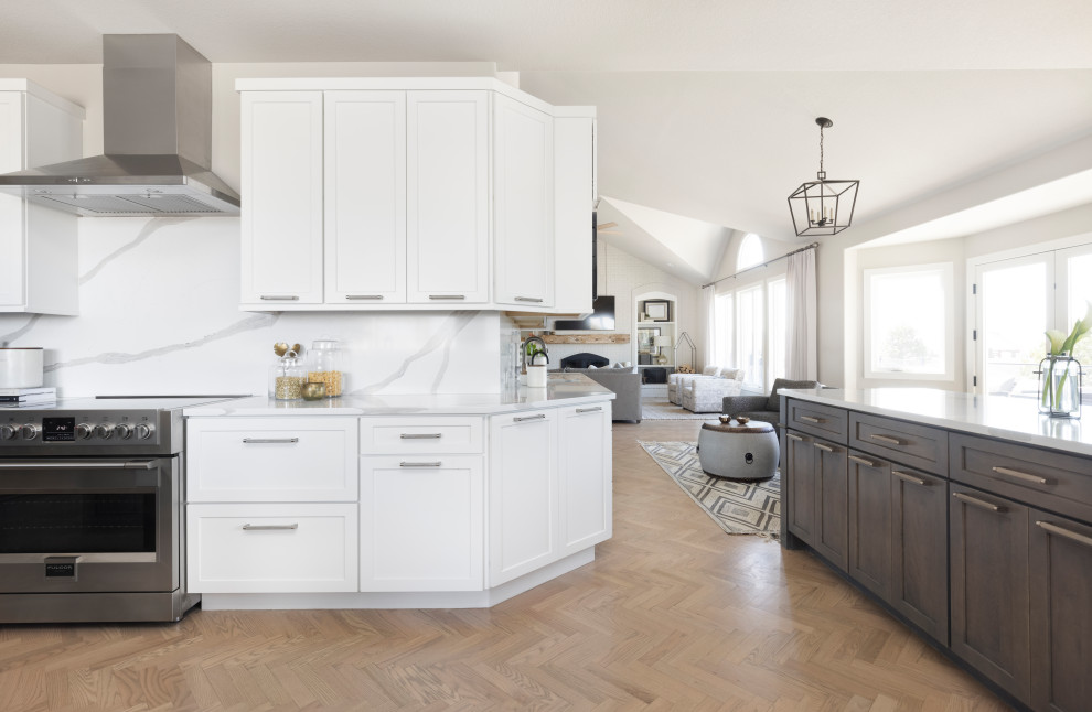 Example of a large transitional l-shaped light wood floor enclosed kitchen design in Denver with a double-bowl sink, shaker cabinets, gray cabinets, quartz countertops, white backsplash, quartz backsplash, stainless steel appliances, two islands and white countertops