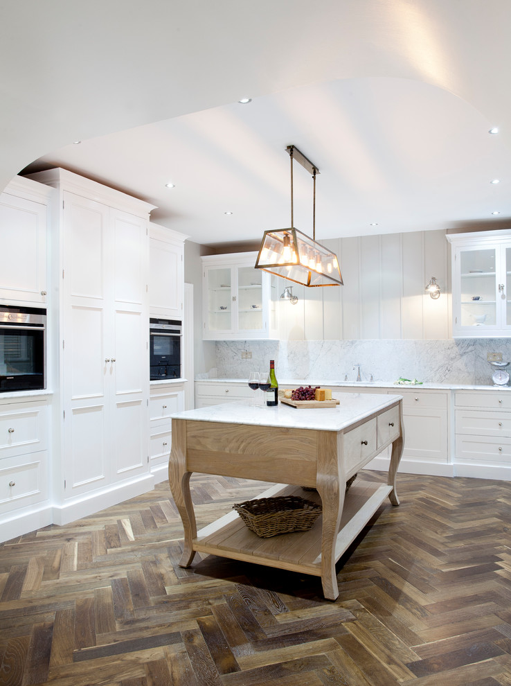 Photo of a large transitional u-shaped kitchen pantry in Dublin with an undermount sink, beaded inset cabinets, white cabinets, marble benchtops, white splashback, stone slab splashback, stainless steel appliances, dark hardwood floors and with island.