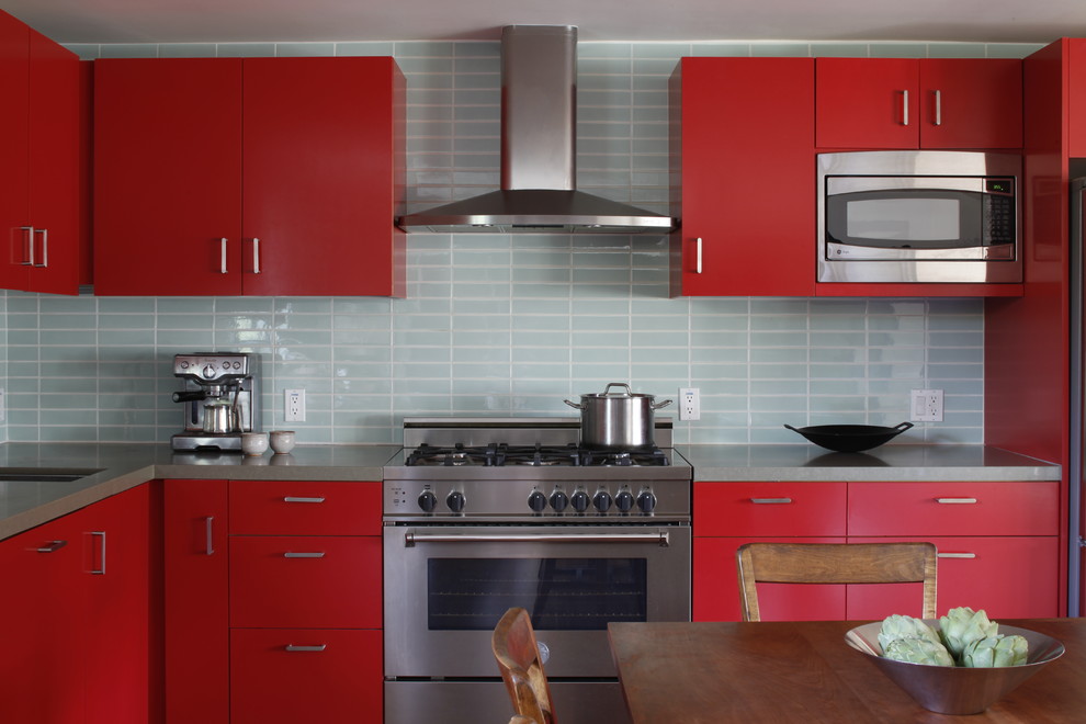 This is an example of a mid-sized modern l-shaped eat-in kitchen in Los Angeles with an undermount sink, flat-panel cabinets, red cabinets, solid surface benchtops, blue splashback, stainless steel appliances, no island and grey benchtop.