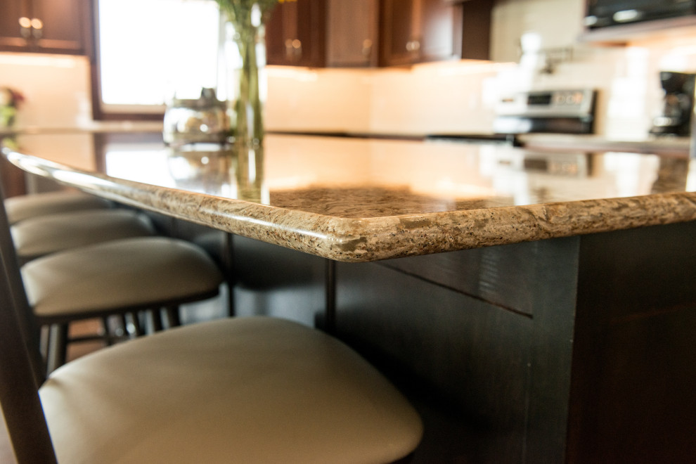 Example of a large transitional l-shaped medium tone wood floor open concept kitchen design with an undermount sink, flat-panel cabinets, medium tone wood cabinets, quartz countertops, white backsplash, ceramic backsplash, stainless steel appliances, an island and multicolored countertops
