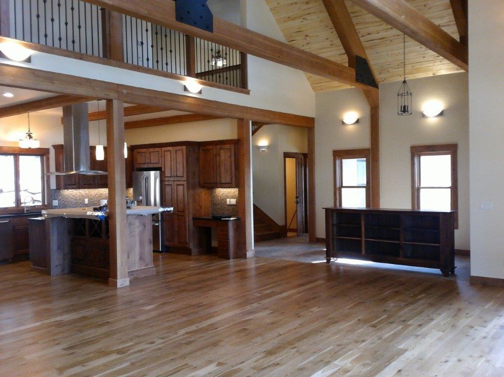 Large mountain style u-shaped medium tone wood floor and brown floor open concept kitchen photo with raised-panel cabinets, dark wood cabinets, an island, an undermount sink, multicolored backsplash, glass tile backsplash and stainless steel appliances