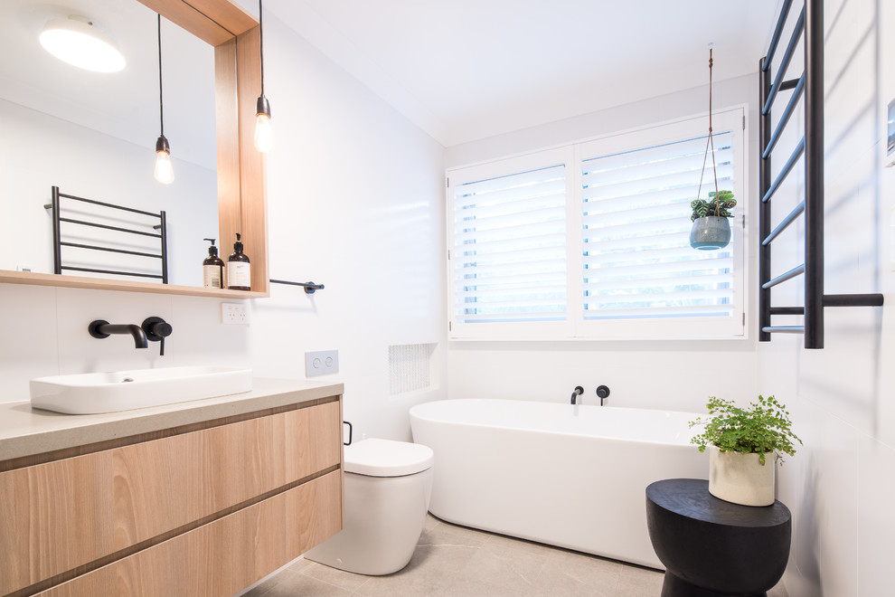 Large contemporary 3/4 bathroom in Central Coast with flat-panel cabinets, light wood cabinets, a freestanding tub, a vessel sink, engineered quartz benchtops, a one-piece toilet, grey floor and beige benchtops.