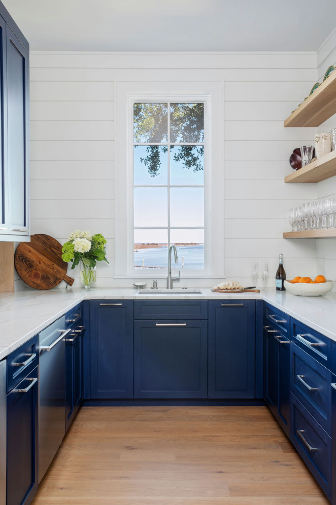 Small beach style galley kitchen pantry in Charleston with a drop-in sink, blue cabinets, marble benchtops, white splashback, shiplap splashback, stainless steel appliances, light hardwood floors, no island, brown floor and white benchtop.