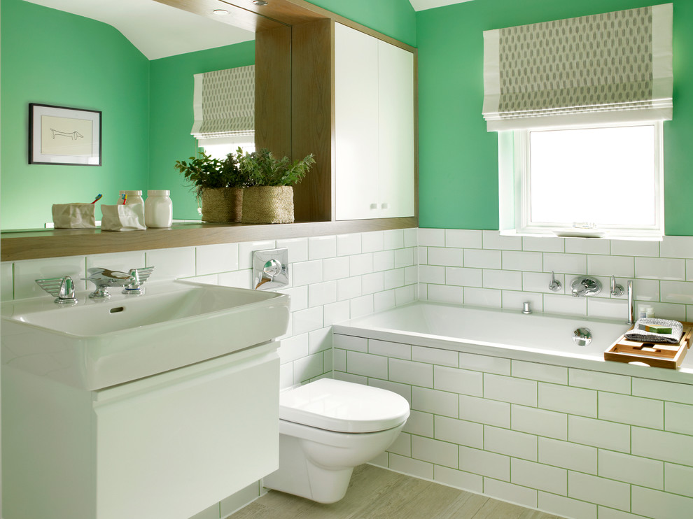 Contemporary bathroom in London with a wall-mount toilet and green walls.