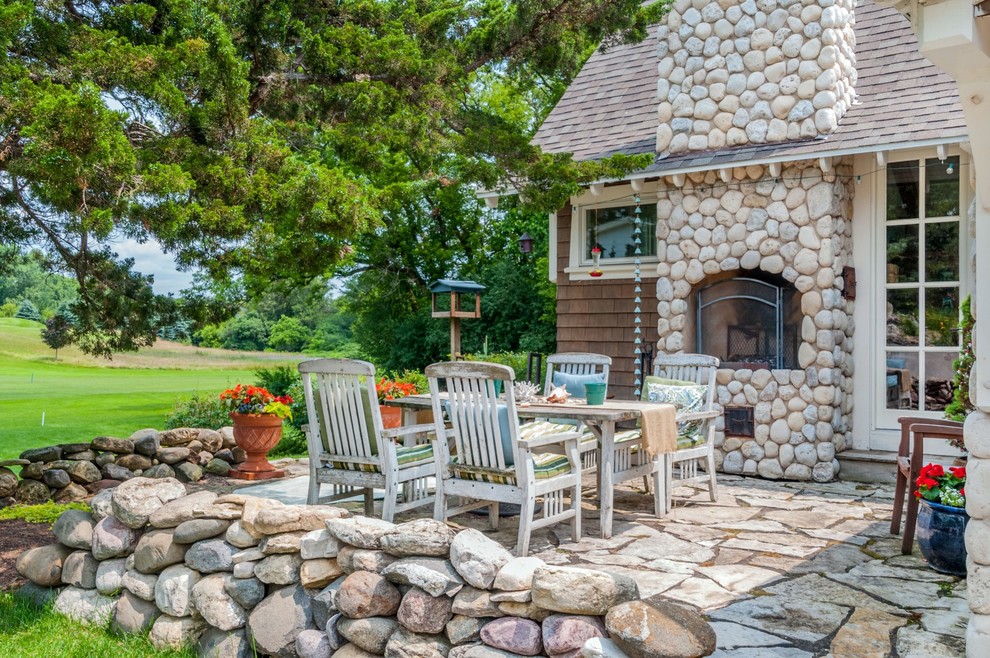 Photo of a mid-sized beach style front yard patio in Milwaukee with a fire feature, natural stone pavers and no cover.