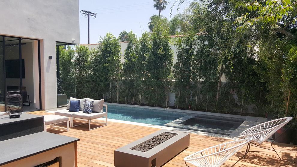 Photo of a mid-sized modern backyard custom-shaped lap pool in Los Angeles with a hot tub and decking.