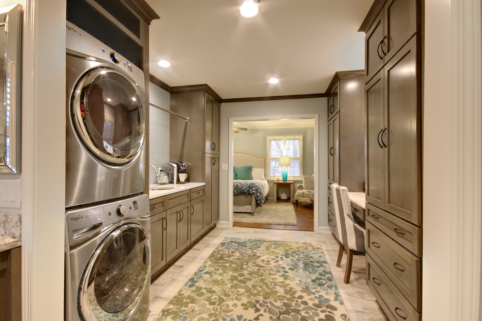 This is an example of an expansive traditional galley utility room in Grand Rapids with an undermount sink, recessed-panel cabinets, grey cabinets, onyx benchtops, ceramic floors, a stacked washer and dryer, grey floor and grey walls.