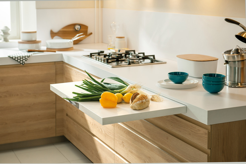 This is an example of a small contemporary l-shaped kitchen in London with white splashback, stainless steel appliances, ceramic floors, light wood cabinets and glass sheet splashback.