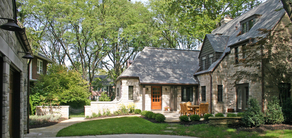 Photo of a mid-sized traditional two-storey house exterior in Other with stone veneer, a gable roof and a tile roof.