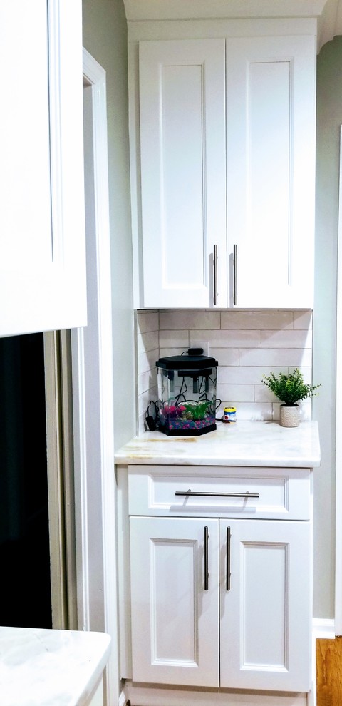 Large transitional u-shaped medium tone wood floor and brown floor enclosed kitchen photo in Miami with an undermount sink, shaker cabinets, white cabinets, quartz countertops, white backsplash, subway tile backsplash, stainless steel appliances, an island and white countertops