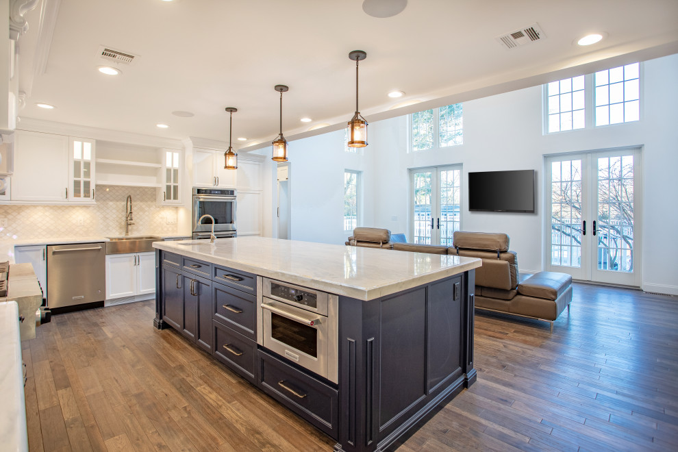 Klassisk inredning av ett stort vit vitt kök, med en undermonterad diskho, skåp i shakerstil, blå skåp, bänkskiva i kvartsit, beige stänkskydd, stänkskydd i keramik, rostfria vitvaror, mellanmörkt trägolv, en köksö och brunt golv