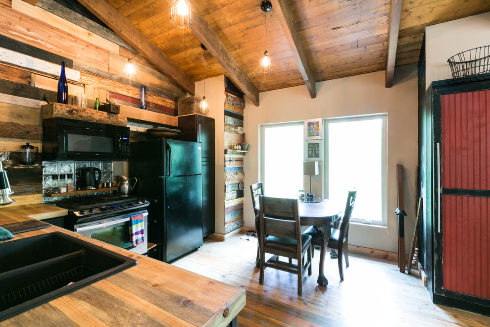 Small country l-shaped eat-in kitchen in Denver with a double-bowl sink, shaker cabinets, black cabinets, wood benchtops, timber splashback, black appliances, medium hardwood floors and no island.