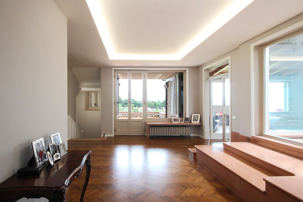 Design ideas for an expansive traditional foyer in Milan with white walls, painted wood floors, a single front door and brown floor.