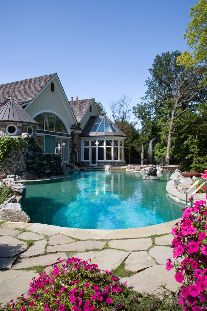 Expansive mediterranean backyard custom-shaped infinity pool in Chicago with natural stone pavers and a hot tub.