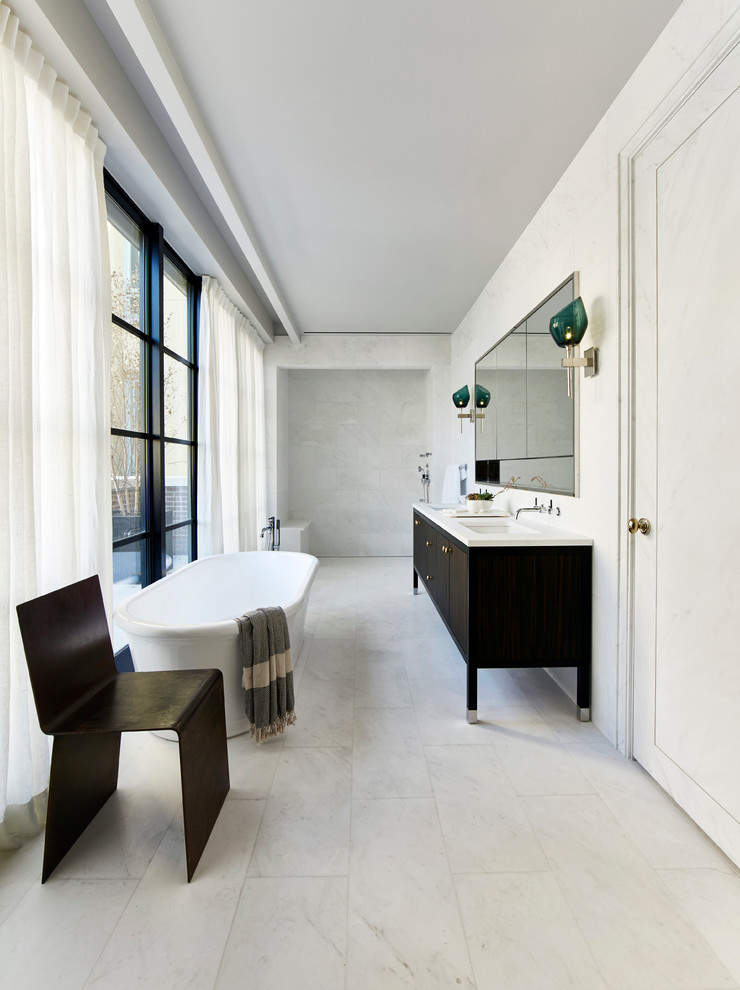 Freestanding bathtub - large modern master marble floor freestanding bathtub idea in New York with flat-panel cabinets, dark wood cabinets, white walls, a drop-in sink and granite countertops