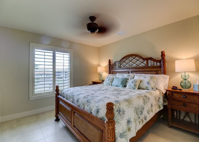 This is an example of a mid-sized beach style guest bedroom in Miami with beige walls, ceramic floors, no fireplace and beige floor.