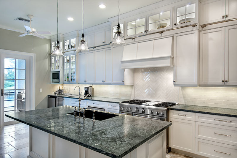 Inspiration for an expansive transitional u-shaped open plan kitchen in Miami with a farmhouse sink, shaker cabinets, white cabinets, quartzite benchtops, white splashback, subway tile splashback, stainless steel appliances, travertine floors and with island.