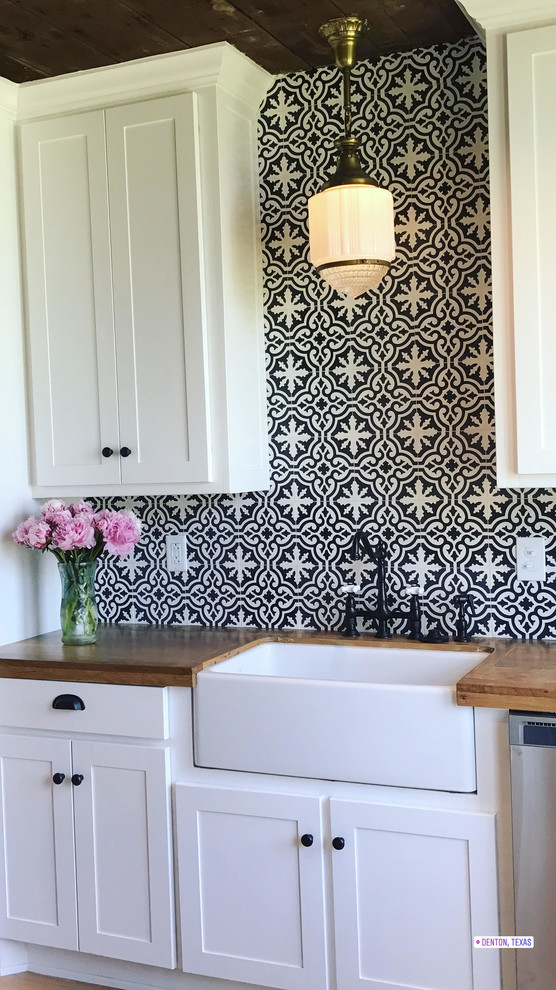 Mid-sized country kitchen in Dallas with cement tile splashback, a farmhouse sink, shaker cabinets, white cabinets, wood benchtops, stainless steel appliances, cement tiles, with island and brown floor.