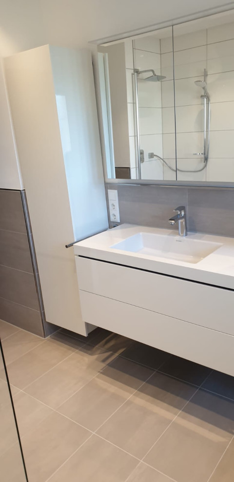 Exempel på ett mellanstort modernt vit vitt badrum med dusch, med släta luckor, vita skåp, en kantlös dusch, en vägghängd toalettstol, beige kakel, porslinskakel, vita väggar, klinkergolv i porslin, ett nedsänkt handfat, beiget golv och med dusch som är öppen