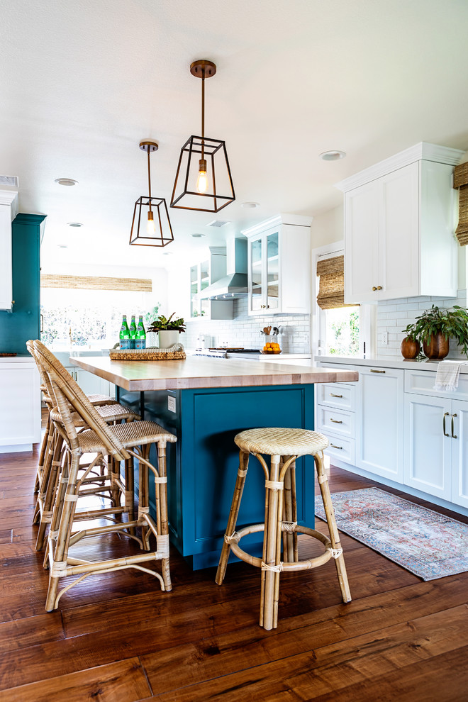 Expansive beach style u-shaped eat-in kitchen in Los Angeles with shaker cabinets, white cabinets, quartzite benchtops, white splashback, subway tile splashback, with island, white benchtop, dark hardwood floors and brown floor.