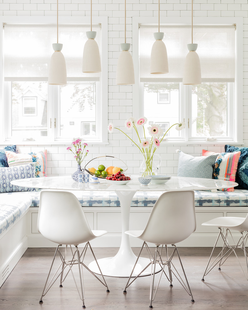Large transitional medium tone wood floor and brown floor kitchen/dining room combo photo in New York with an undermount sink, flat-panel cabinets, white cabinets, quartz countertops, white backsplash, subway tile backsplash, stainless steel appliances, an island and white walls