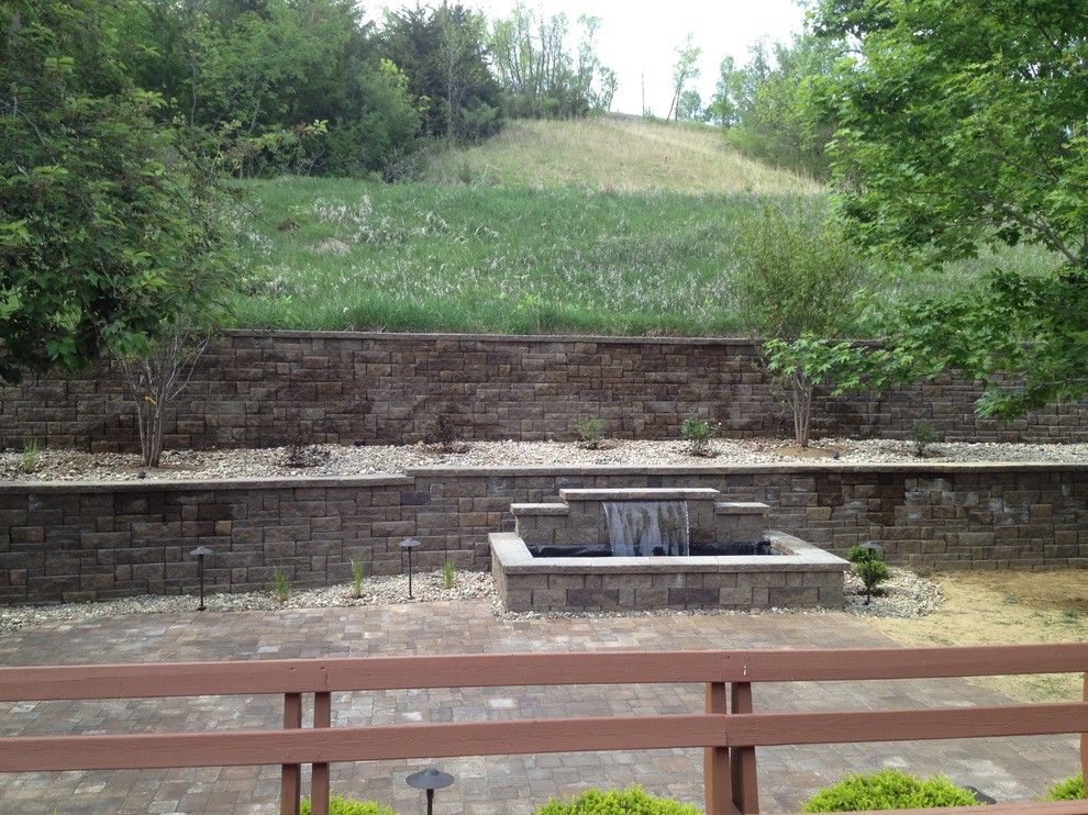 This is an example of a mid-sized traditional backyard garden in Omaha with a retaining wall and brick pavers.