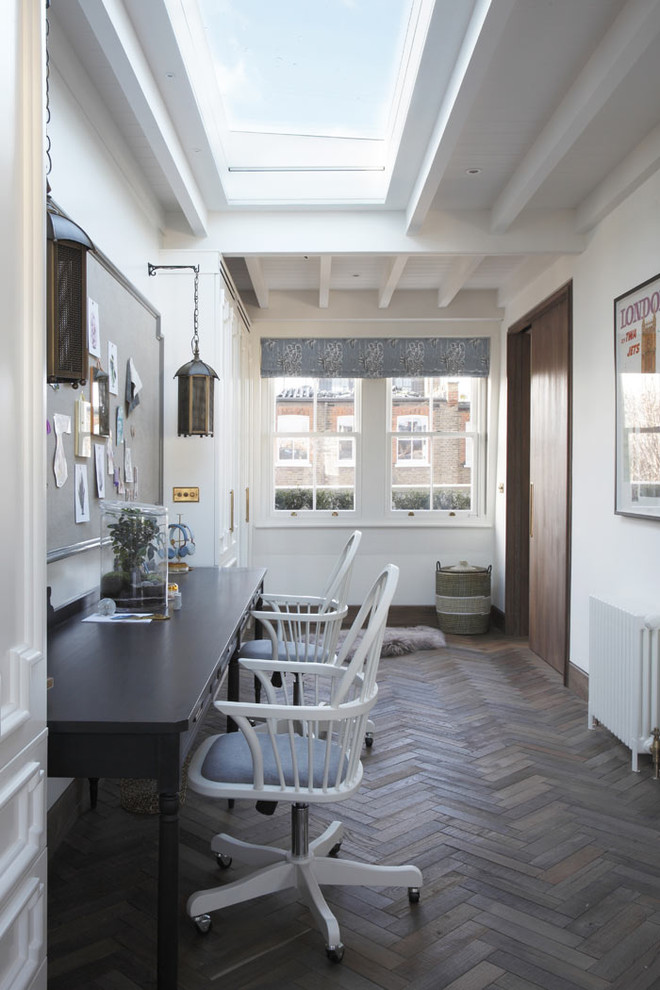 Mid-sized traditional study room in London with white walls, dark hardwood floors, a freestanding desk and brown floor.