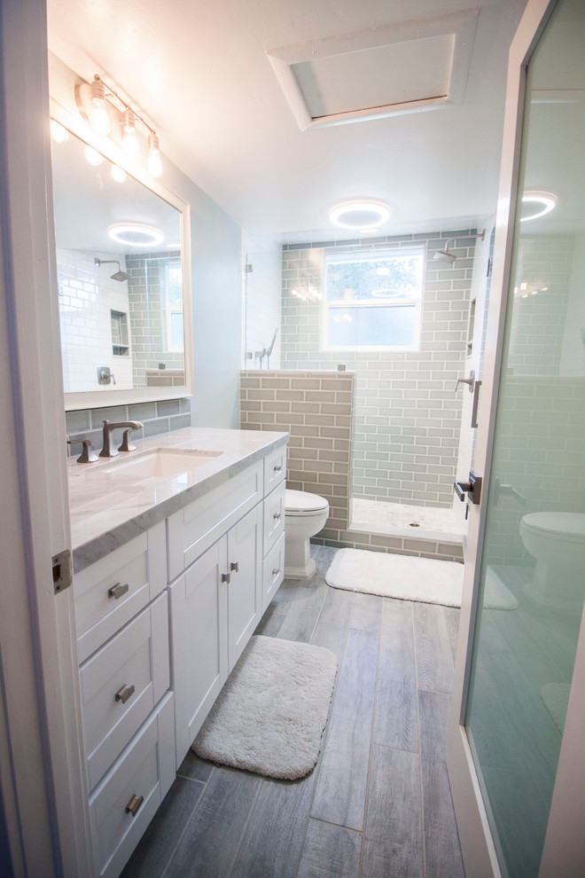 Small contemporary 3/4 bathroom in Los Angeles with shaker cabinets, white cabinets, an alcove shower, a one-piece toilet, blue tile, glass tile, blue walls, porcelain floors, an undermount sink and marble benchtops.