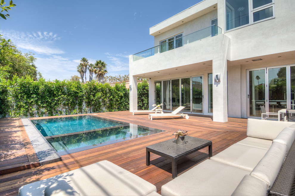 This is an example of a large contemporary backyard rectangular infinity pool in Los Angeles with decking.