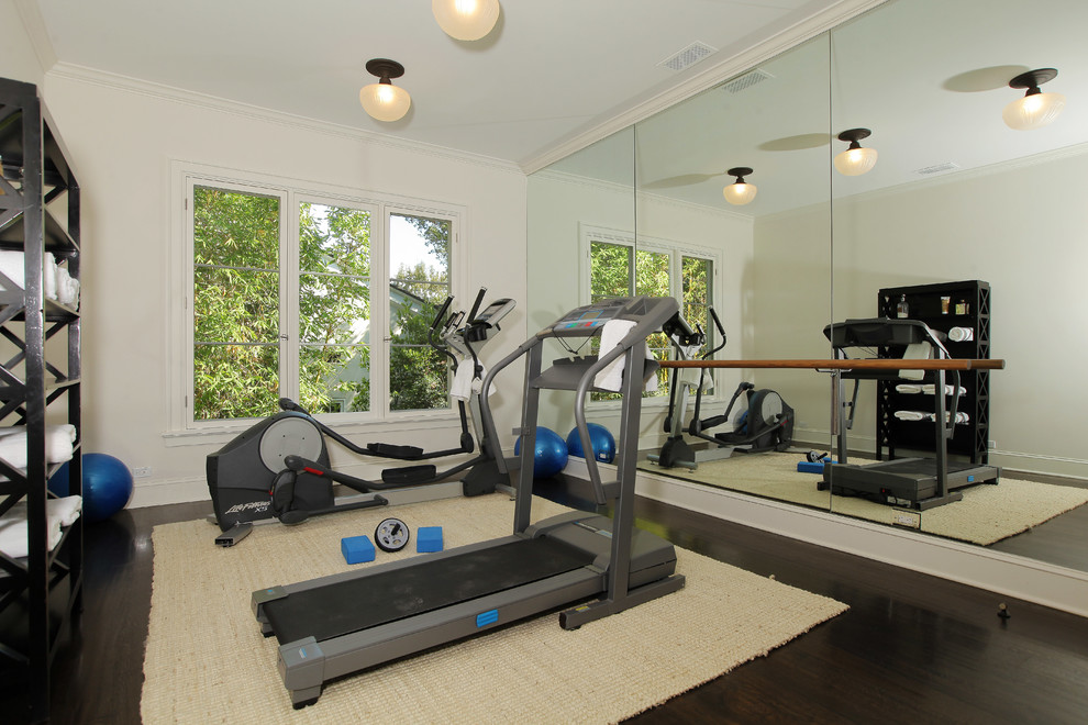 This is an example of a traditional home gym in Los Angeles with white walls and dark hardwood floors.