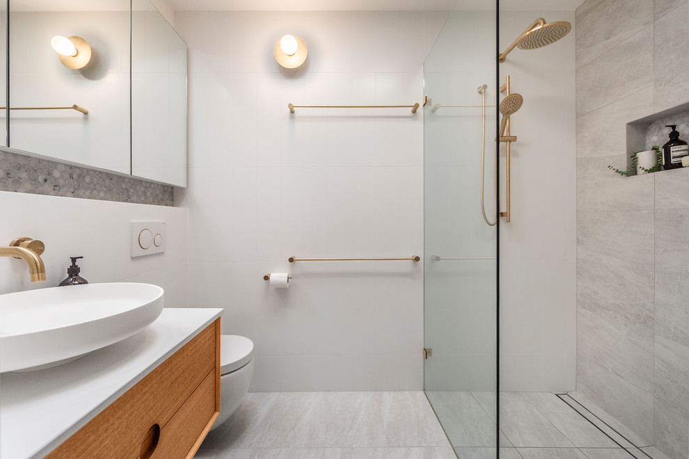 This is an example of a mid-sized contemporary master bathroom in Melbourne with flat-panel cabinets, white tile, gray tile, porcelain floors, engineered quartz benchtops, grey floor, an open shower, white benchtops, medium wood cabinets, a curbless shower, a wall-mount toilet and a vessel sink.
