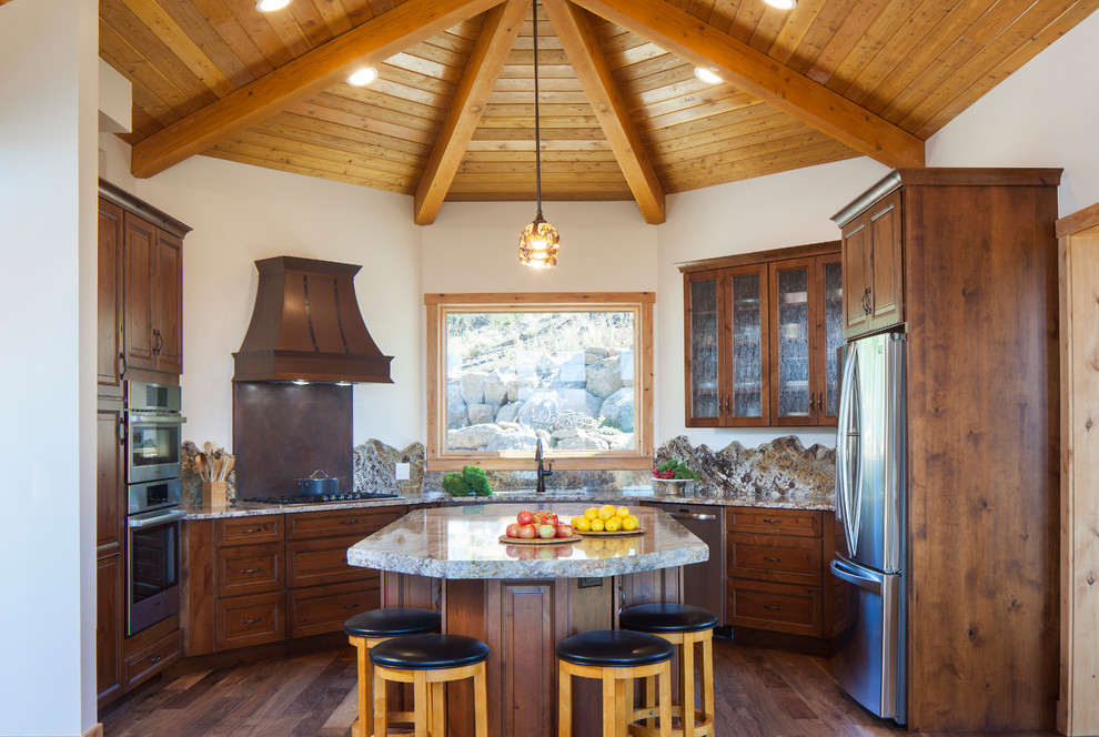 Example of a mountain style brown floor and dark wood floor kitchen design in Denver with dark wood cabinets, granite countertops, stainless steel appliances, an island, brown backsplash, multicolored countertops and recessed-panel cabinets
