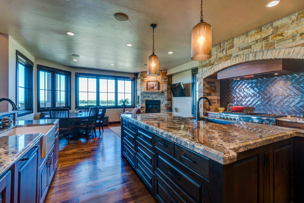 Large arts and crafts open plan kitchen in Denver with a farmhouse sink, raised-panel cabinets, medium wood cabinets, granite benchtops, grey splashback, subway tile splashback, panelled appliances, medium hardwood floors, with island and brown floor.
