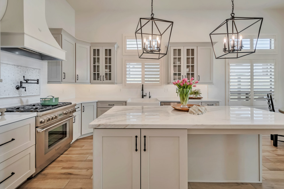 Inspiration for a large transitional u-shaped porcelain tile, brown floor and exposed beam kitchen remodel in Phoenix with a farmhouse sink, shaker cabinets, gray cabinets, quartzite countertops, white backsplash, porcelain backsplash, stainless steel appliances, an island and white countertops