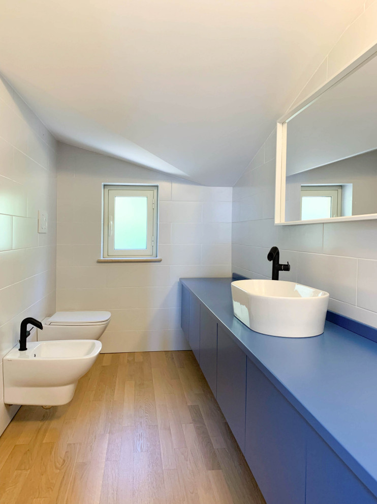 На фото: маленькая ванная комната в средиземноморском стиле с фасадами с декоративным кантом, синими фасадами, душем в нише, инсталляцией, белой плиткой, керамогранитной плиткой, белыми стенами, светлым паркетным полом, настольной раковиной, столешницей из дерева, коричневым полом, душем с распашными дверями, синей столешницей, тумбой под одну раковину, подвесной тумбой и многоуровневым потолком для на участке и в саду с