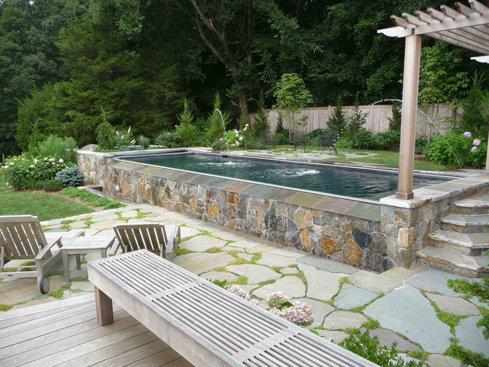 This is an example of a mid-sized beach style backyard rectangular aboveground pool in Bridgeport with natural stone pavers and a water feature.