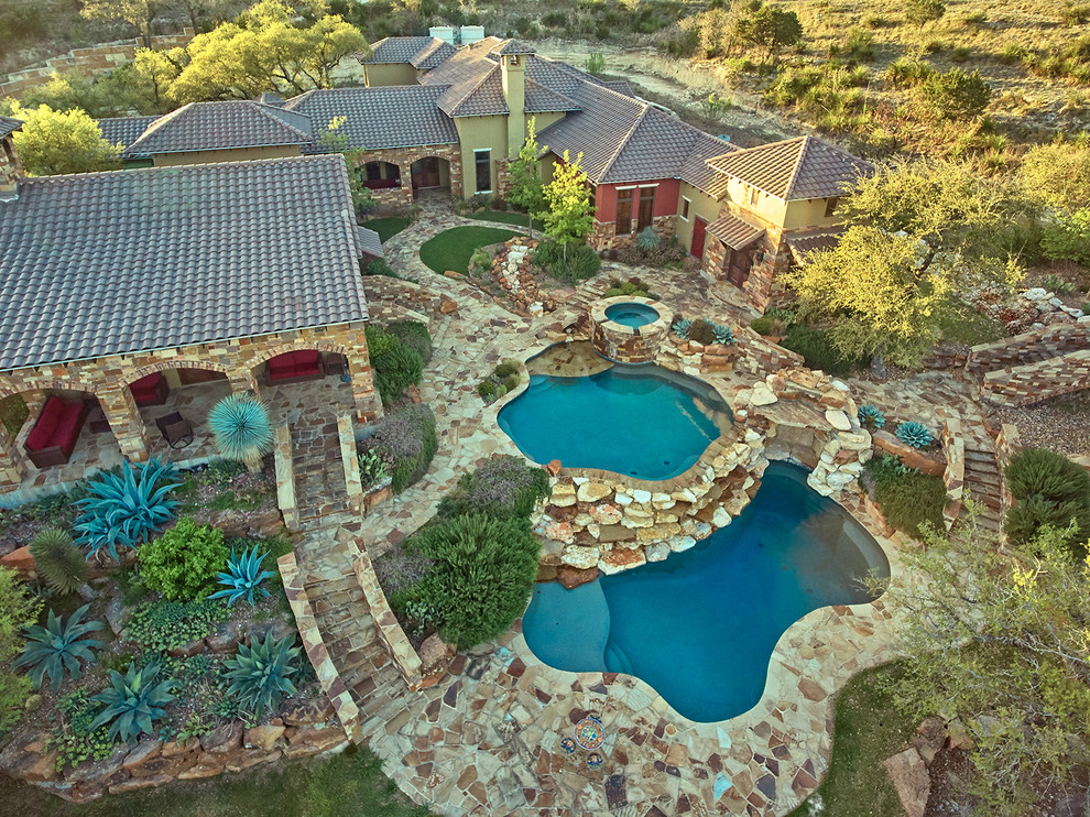 Inspiration for a large rustic backyard stone and custom-shaped hot tub remodel in Austin