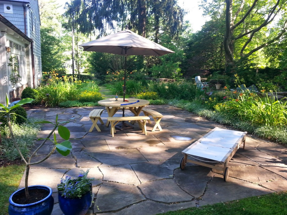 Photo of a medium sized eclectic back patio in New York with a water feature, natural stone paving and no cover.
