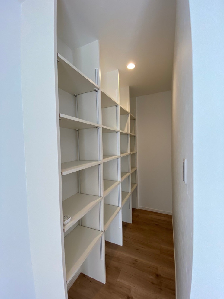 Ejemplo de armario vestidor unisex de tamaño medio con armarios abiertos, puertas de armario blancas, suelo de madera en tonos medios, suelo marrón y papel pintado