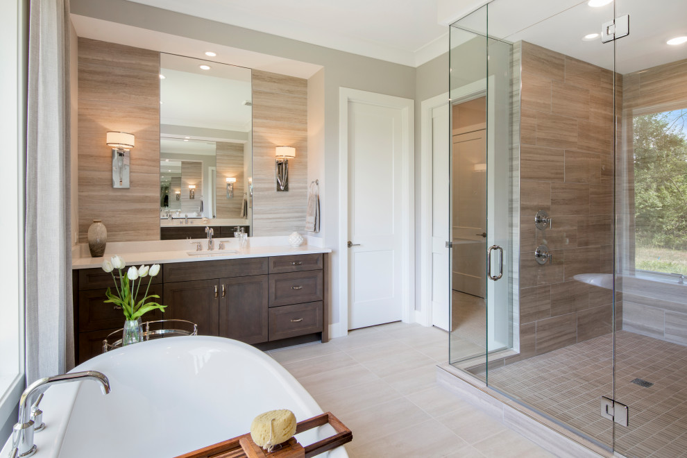 Photo of a transitional bathroom in Cincinnati with recessed-panel cabinets, dark wood cabinets, a freestanding tub, a corner shower, beige tile, grey walls, an undermount sink, beige floor, a hinged shower door, white benchtops, an enclosed toilet, a single vanity and a built-in vanity.